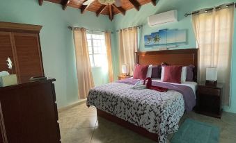 a spacious bedroom with a large bed and wooden ceiling , under a sloped ceiling with windows at Ocean View Villas