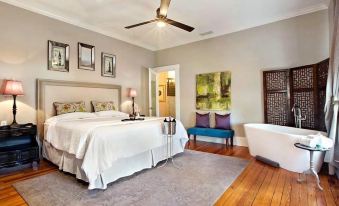 a luxurious bedroom with a large bed , a bathtub , and hardwood floors , surrounded by walls and artwork at Sparrow Grove Manor
