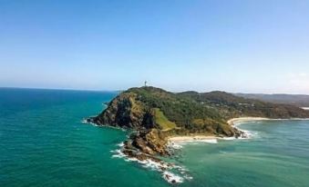 aerial view of a small island surrounded by water , with a lighthouse visible in the distance at YHA Byron Bay