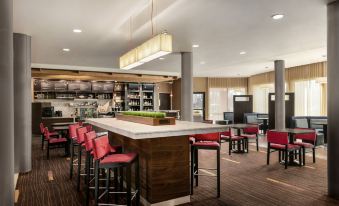 a modern restaurant with a bar area and a dining table , where several people are seated and enjoying their meals at Courtyard Burlington Mt. Holly/Westampton