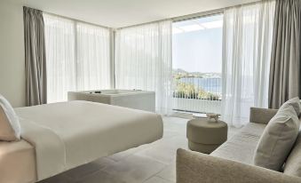 a luxurious bedroom with a large bed and a bathtub , overlooking a beautiful view of the ocean at Radisson Resort Skiathos