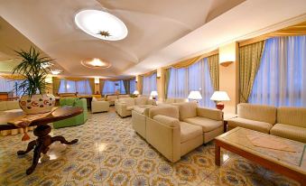 a spacious , well - lit living room with multiple couches and chairs arranged in various positions around the room at Grand Hotel Terme di Augusto