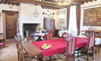 a dining room with a table set for a meal , surrounded by chairs and a fireplace at Le Chateau