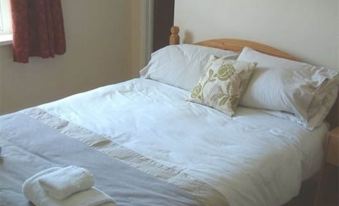 a neatly made bed with white sheets and pillows , surrounded by towels and a window at The Royal Oak