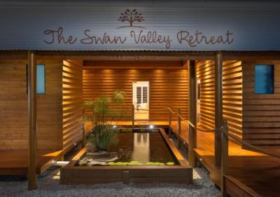 "a wooden building with a sign that reads "" the swan valley retreat "" above a small pond" at The Swan Valley Retreat