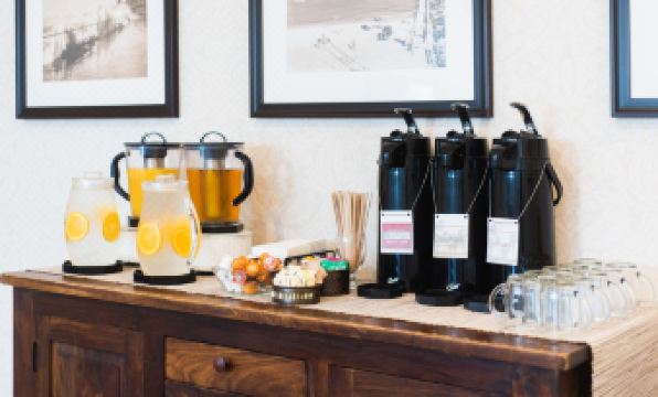 a wooden counter with various beverages and snacks , including orange juice , is displayed next to framed pictures at Hotel Santa Barbara