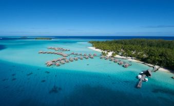 aerial view of a beautiful beach with turquoise water , surrounded by wooden cabins and boats at Le Bora Bora by Pearl Resorts
