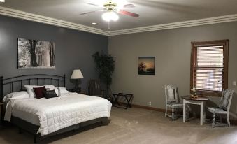 a spacious bedroom with a large bed , a dining table , and a ceiling fan hanging from the ceiling at Oak Creek Lodge