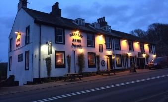 a nighttime street scene with a white building on the left side of the road at Stanley Arms Hotel