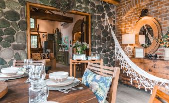 a dining room with a wooden table set for two , surrounded by chairs and a hammock hanging from the ceiling at Hacienda la Danesa