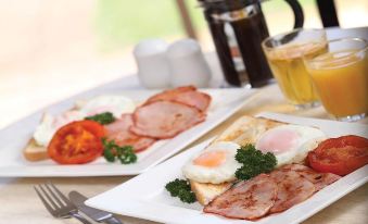 a table with two plates of food , including eggs and bacon , placed on it , accompanied by a glass of beer at Murray Downs Resort