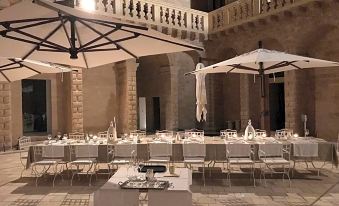 a long dining table set up for a special occasion , with white chairs and umbrellas arranged around it at Castello di Ugento