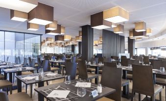 a modern restaurant with many dining tables and chairs , creating a comfortable atmosphere for guests at Hotel Bristol 4 Sup