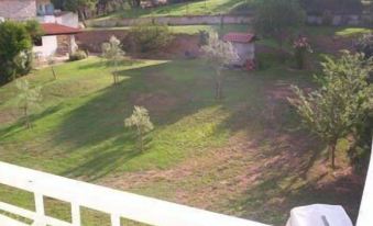 a view of a yard from a balcony , with trees and a building in the background at Milos Apartments