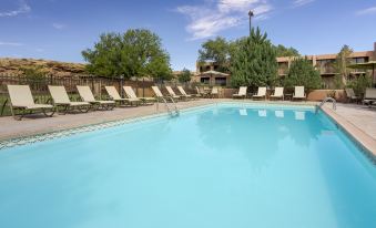 a large swimming pool surrounded by lounge chairs and umbrellas , with a building in the background at Holiday Inn Canyon de Chelly (Chinle)