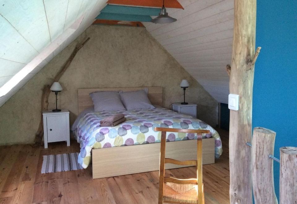 a cozy bedroom with wooden beams , blue walls , and a bed made up with colorful bedding at La Vieille Ferme