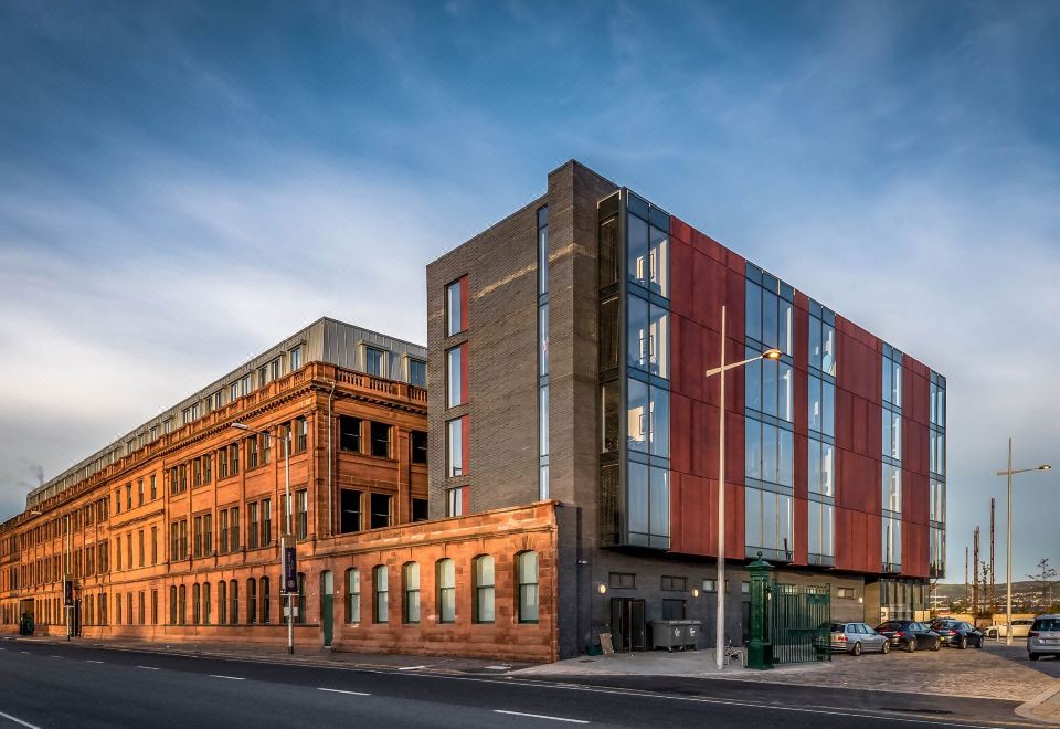 a modern building with a red and blue facade is situated on a street corner at Titanic Hotel Belfast