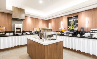 a well - equipped kitchen with a dining table and chairs , as well as a buffet filled with various food items at Hotel WelcomInns