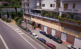 a city street with several cars parked along the side of the road , and a building with balconies at Hotel Sole