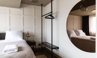 a white bedroom with a bed , a mirror , and a hanging chair , reflecting the room 's interior at Mr Lewis Zandvoort