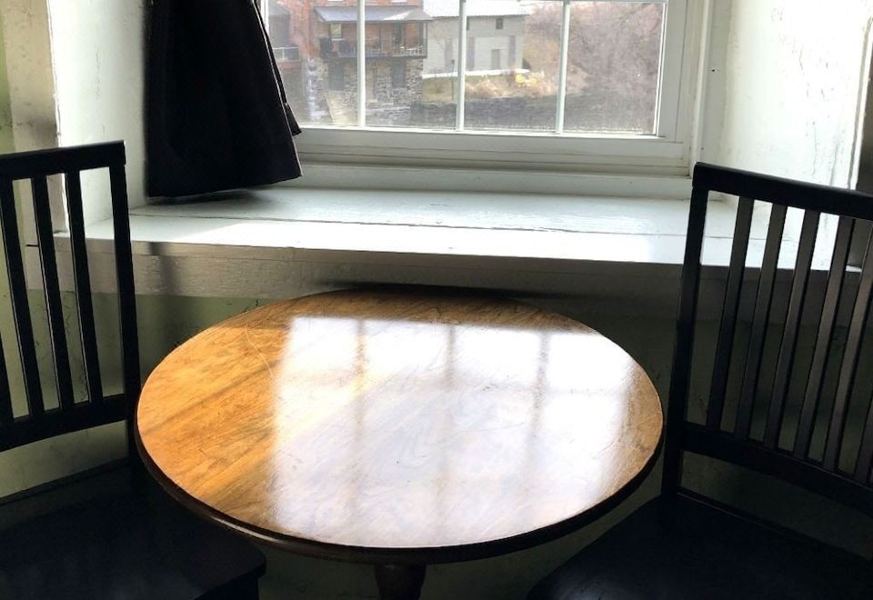 a wooden dining table with black chairs in front of a window , providing a view of the outside at The Inn at Stone Mill