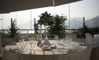 a well - set table with a view of the mountains , wine glasses , and a centerpiece in front of it at Grand Hotel Salerno
