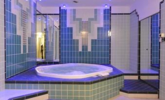 a large indoor pool with blue and white tiles , a circular hot tub , and two people standing near the wall at Hotel Moderno