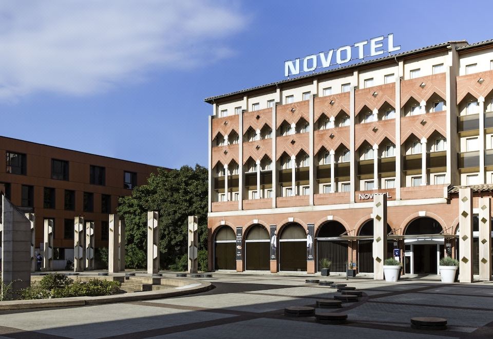 "a modern hotel building with the name "" novotel "" prominently displayed on its facade , surrounded by trees and other buildings" at Novotel Toulouse Centre Compans Caffarelli