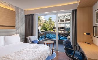 a hotel room with a bed , chair , and sliding glass door leading to a pool at Le Méridien Goa, Calangute