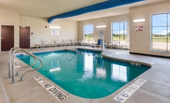 a large swimming pool with a diving board and chairs is shown in an indoor setting at Cobblestone Hotel & Suites - Two Rivers