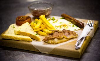 a wooden cutting board filled with a variety of food items , including meat , bread , and french fries at Hotel Savera