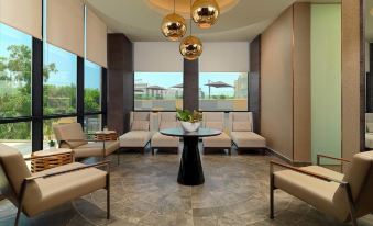 a modern living room with beige walls , large windows , and comfortable seating arrangements , including a dining area at Radisson Blu Hotel, Bamako