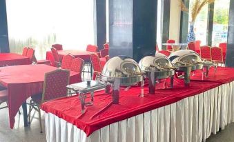 a dining room with a long table covered in a red tablecloth , surrounded by several chairs at Hotel Prima Indah