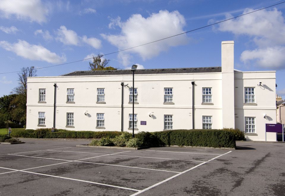 a white building with many windows and a parking lot in front of it , under a clear blue sky at Arundel