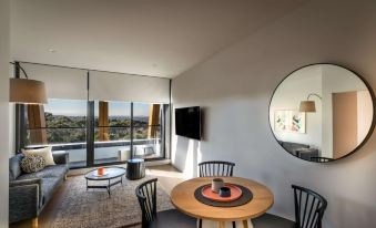 a modern living room with a round table , chairs , and a large window overlooking the city at Punthill Ivanhoe