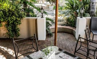 an outdoor dining area with a table set for two , surrounded by potted plants and a stone walkway at Oxford Lodge Vryheid