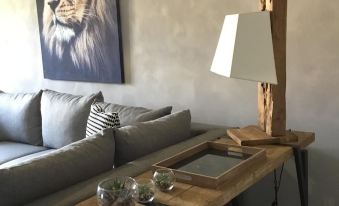 a living room with a gray couch , wooden coffee table , and a lion painting on the wall at Marina