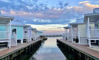 a row of colorful houses on stilts , with a boat docked in front of them at Key West Cottages