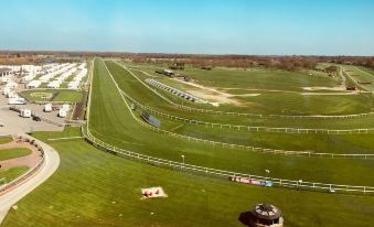 aerial view of a horse race track surrounded by green grass and trees , with spectators on the sidelines at Hilton Garden Inn Doncaster Racecourse