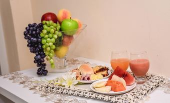 a dining table with a variety of fruits , including apples , oranges , grapes , and watermelon , as well as a bowl of at Prime Hotel