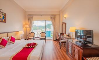 a bedroom with a bed , desk , chairs , and a television is shown with a view of the ocean at Seagull Hotel