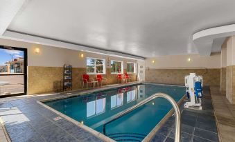 an indoor swimming pool with a clear blue water , surrounded by chairs and tables , in a modern building at Quality Inn Denver Northeast Brighton