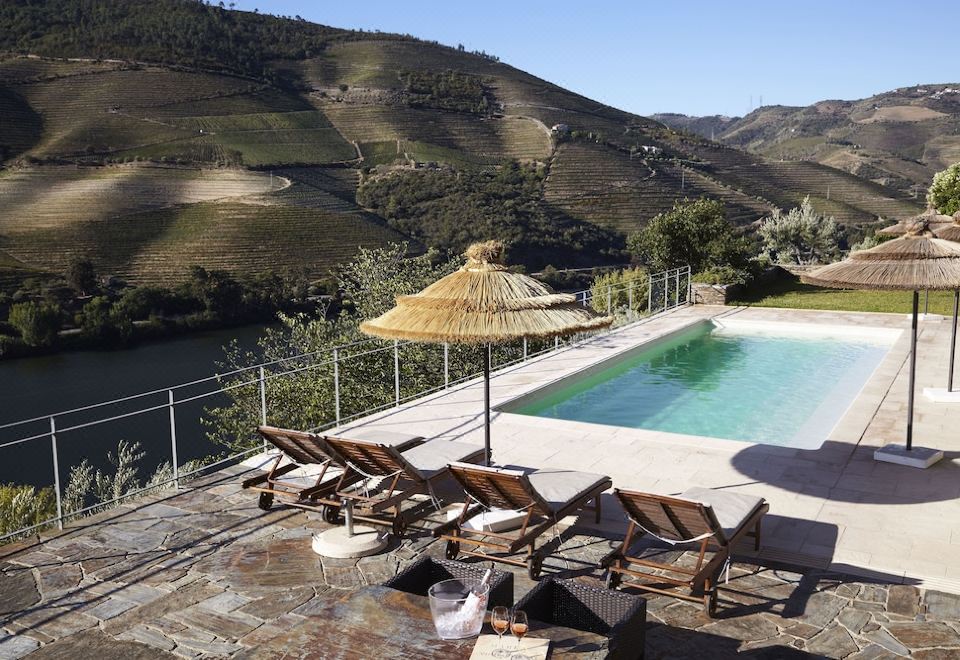 a large outdoor pool surrounded by a wooden deck , with several lounge chairs placed around it at Quinta Da Marka