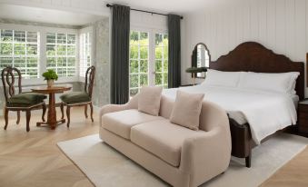 a cozy bedroom with a white bed , a couch , and a dining table in the room at The Inn at Rancho Santa Fe