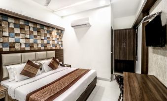 a modern hotel room with a large bed , wooden furniture , and an air conditioner on the ceiling at Hotel Kings