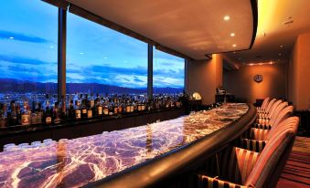 a modern bar with large windows offering a view of the city , illuminated by blue lights and dimly lit atmosphere at Hotel Metropolitan Nagano