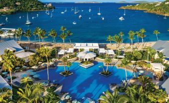a resort with a large pool surrounded by palm trees and a beach , with several boats in the water at The Westin St. John Resort Villas