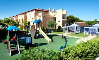 a playground with a slide , swings , and other play equipment in front of an apartment building at Grupotel Club Turquesa Mar