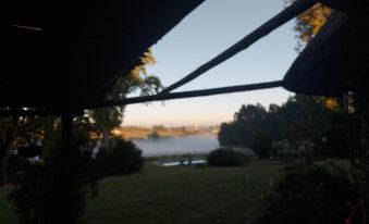 a view of a foggy lake from a window with trees and bushes in the foreground at Little Milton