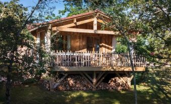 a wooden house with a balcony and a deck , surrounded by trees and bushes , is shown in the image at Le Lion d'Or en Perigord